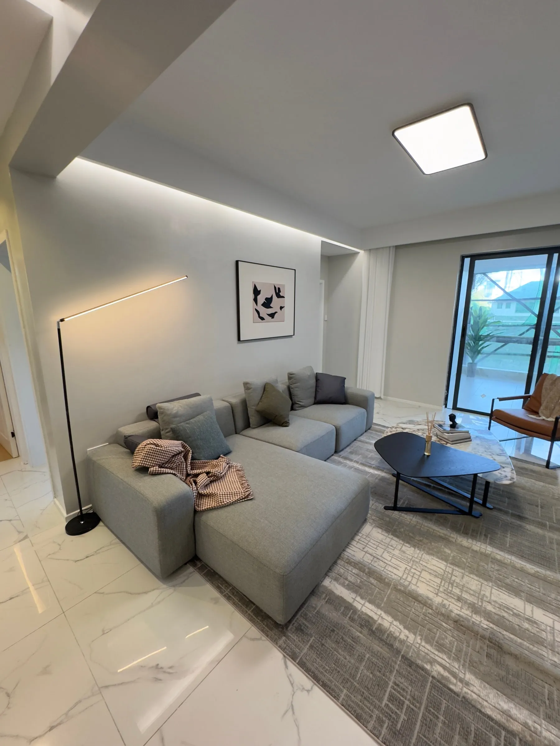 Grey corner sofa and coffee table beside a full-height window