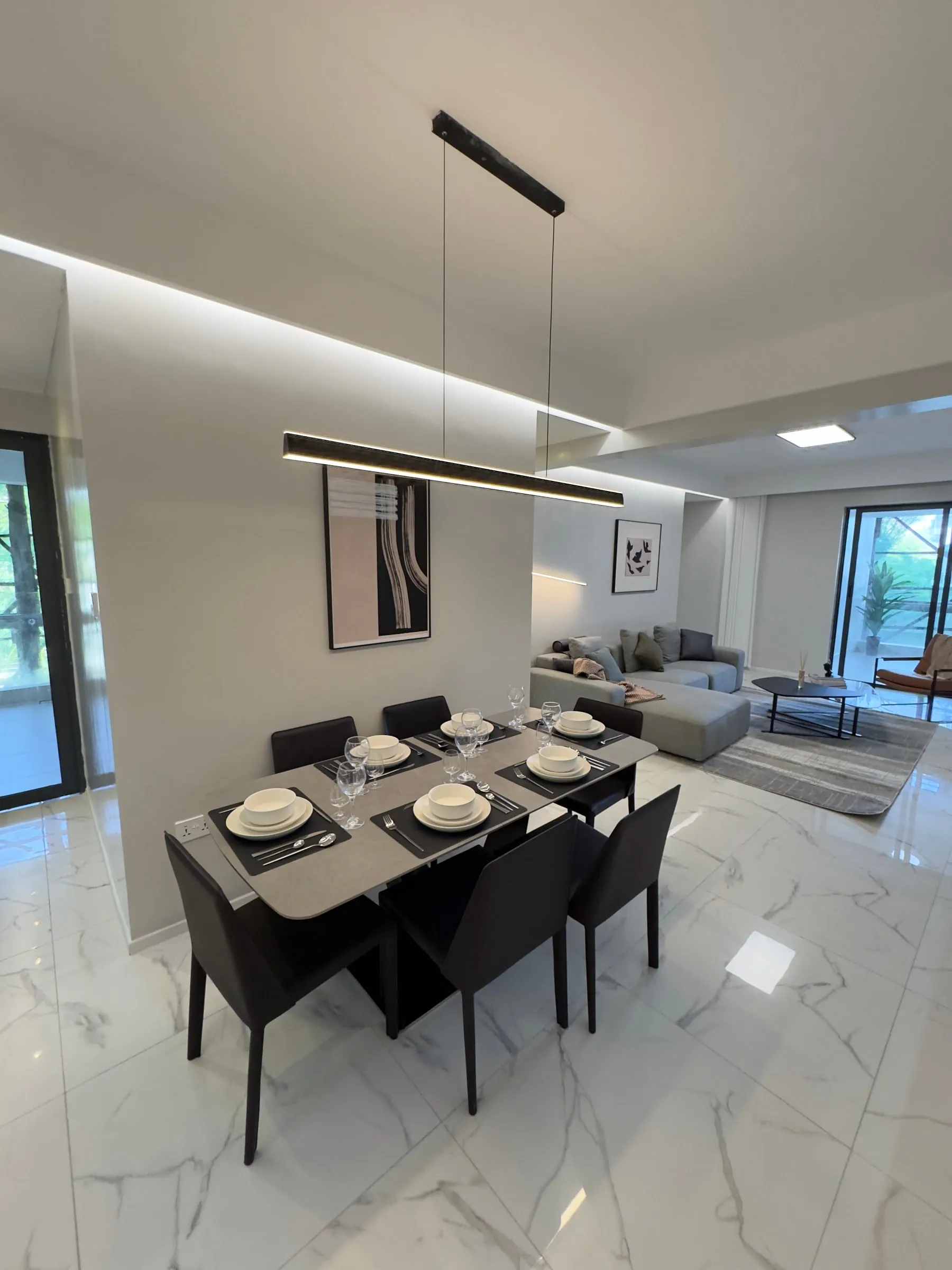 Open-plan dining and living room in the furnished show house, with the balcony door at the far end