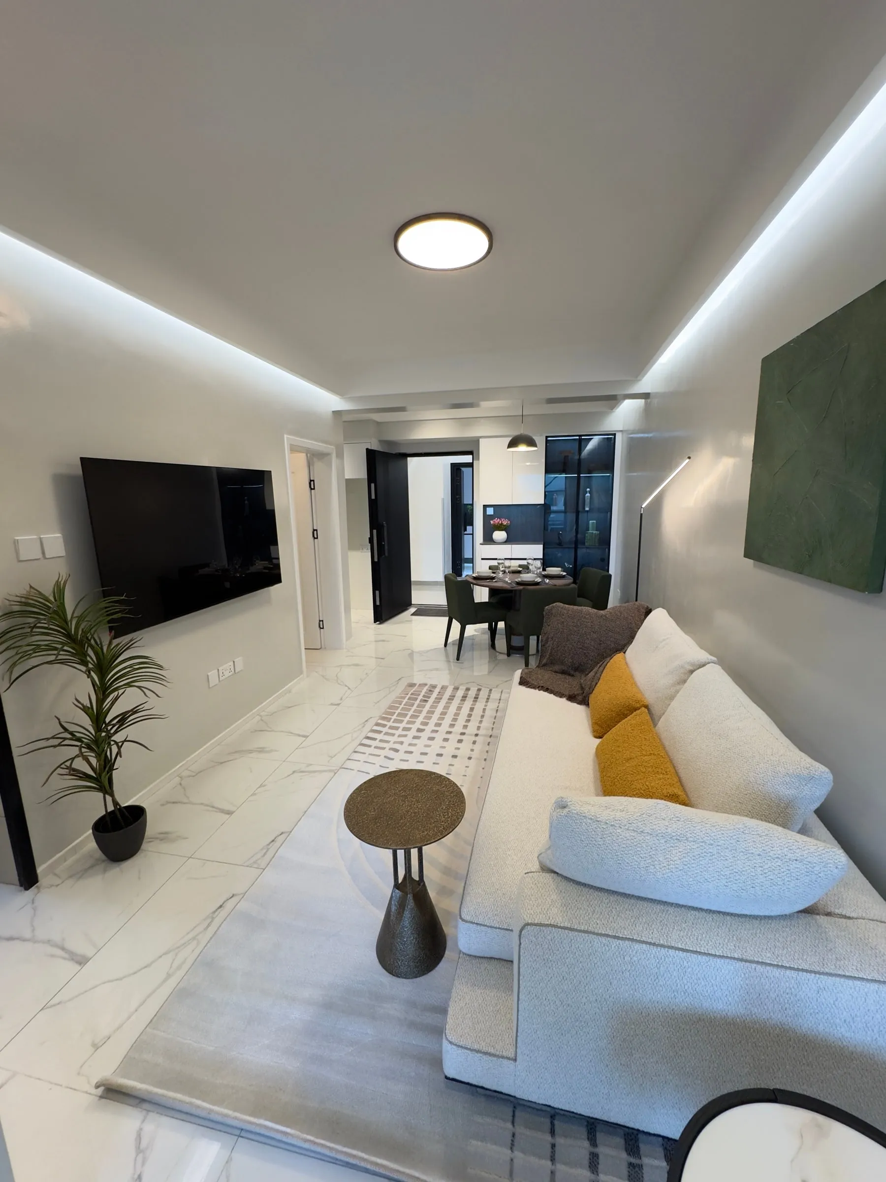 Living room with a white sofa, wall-mounted TV and view to the dining area