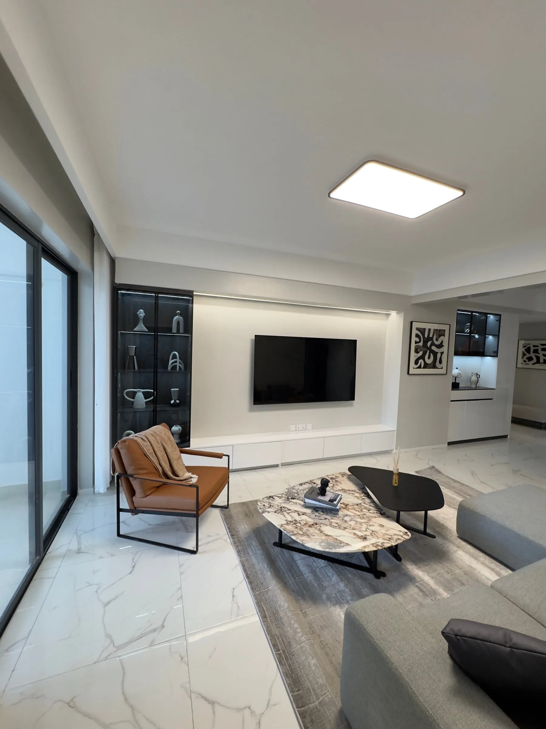 Living room with a display cabinet, TV wall and sliding balcony doors
