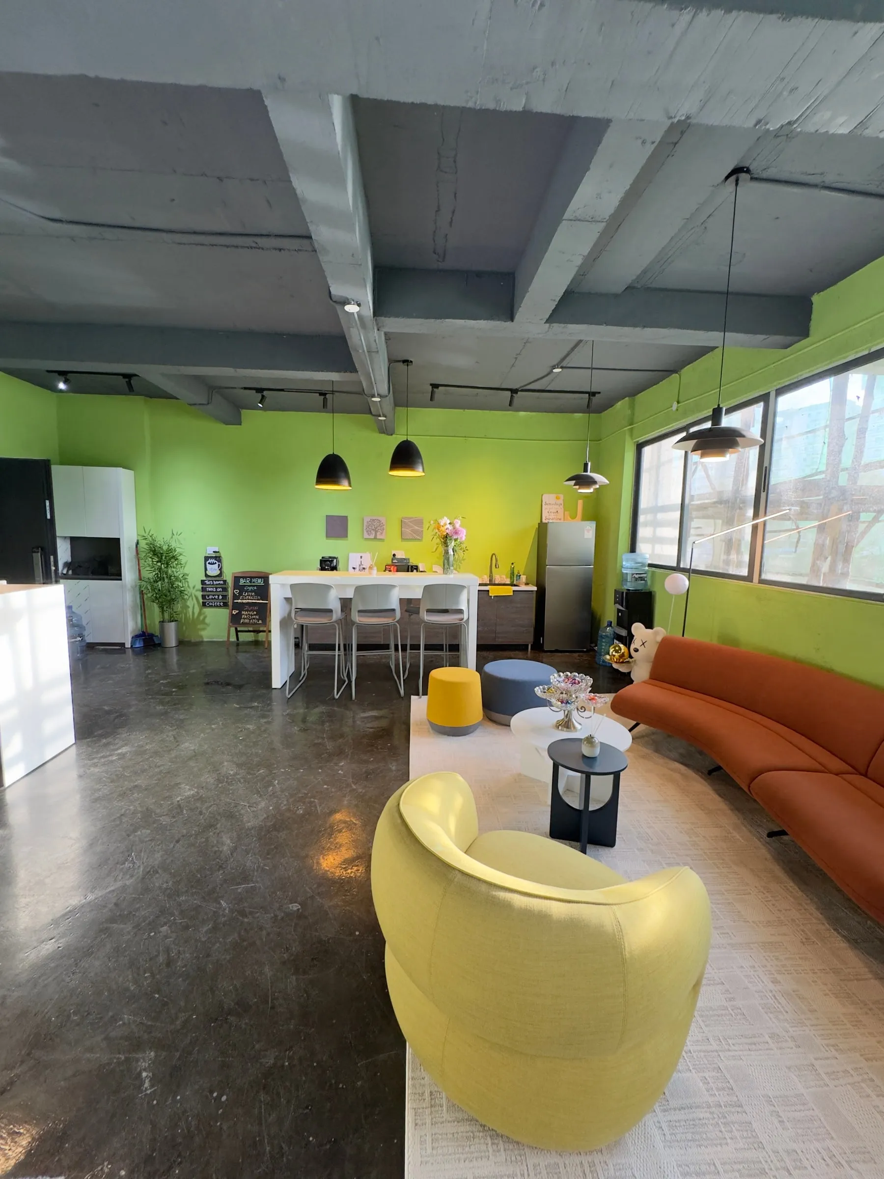 The ILU Green Homes sales office: a lounge with a yellow armchair and orange sofa, and a bar counter with stools